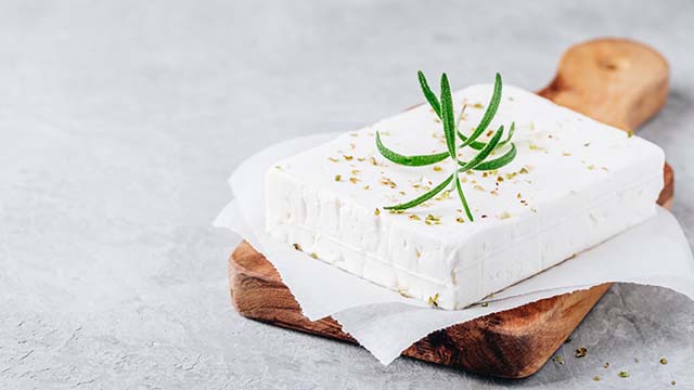 block of feta cheese on wooden cutting board 640x360